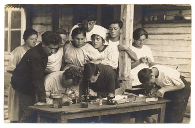 A group of students examines a specimen under a microscope at a summer camp. Puszkarnia, Poland (now Lithuania), 1922.
Photograph by D. G. Aliber. From the Archives of the YIVO Institute for Jewish Research, New York.